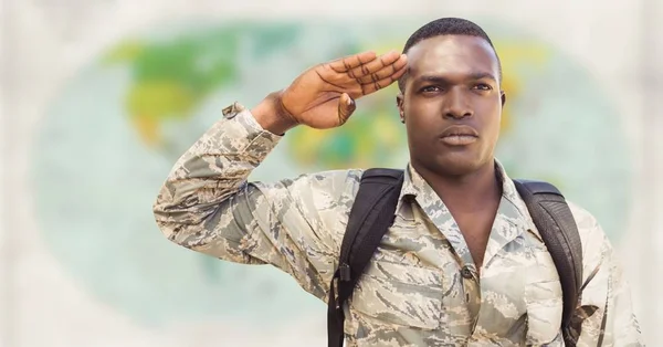 Soldier with backpack saluting against blurry map — Stock Photo, Image