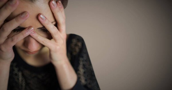 Женщина закрывает лицо на коричневом фоне
