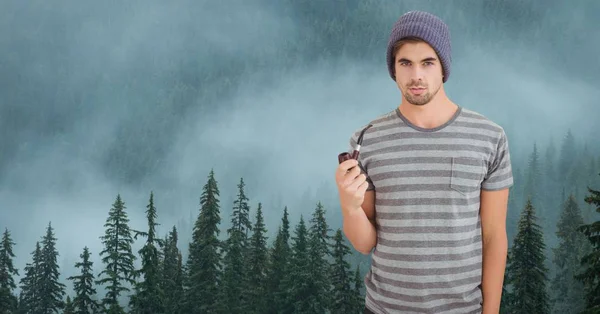 Hipster holding smoking pipe against fog covering forest — Stock Photo, Image