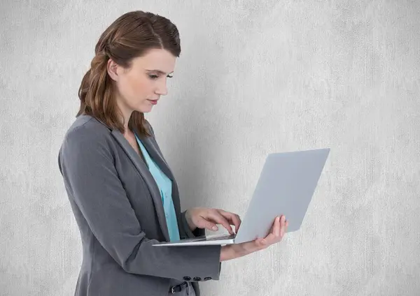 Бизнесмен, использующая ноутбук к стене — стоковое фото