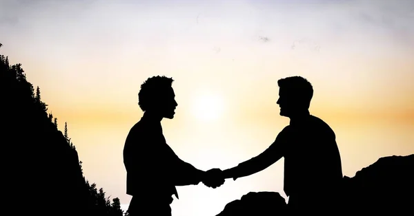 Бизнесмены силуэта пожимают друг другу руки на закате — стоковое фото