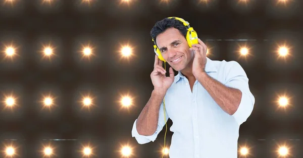 Hombre feliz escuchando música con luces en el fondo —  Fotos de Stock