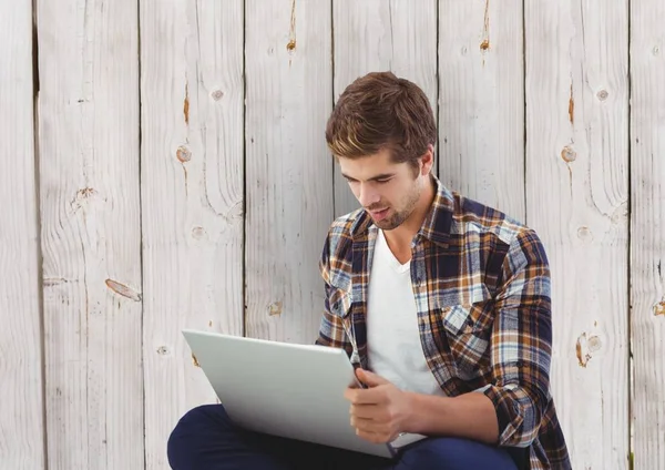 Zakenman met behulp van laptop tegen een houten muur — Stockfoto