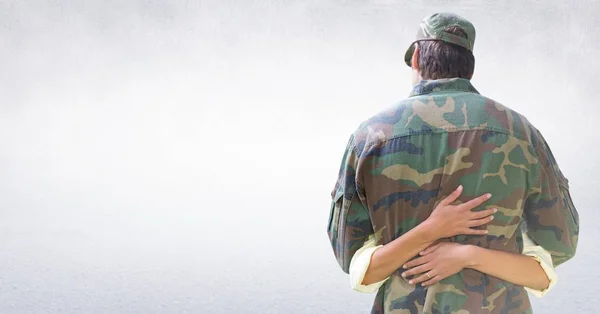 Costas de soldado abraçando contra a parede branca — Fotografia de Stock