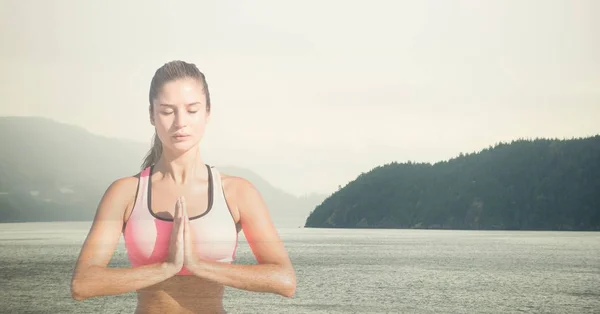 Femme méditant contre le lac — Photo