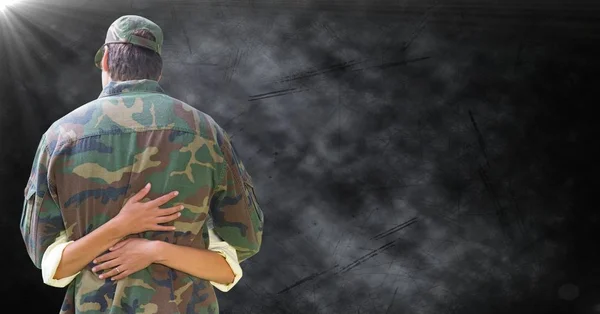 Achterkant soldaat wordt geknuffeld tegen zwarte grunge achtergrond met flare — Stockfoto