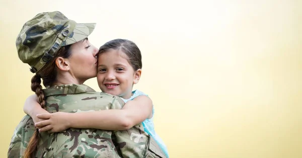 Soldier mother and daughter against yellow background — Stock Photo, Image