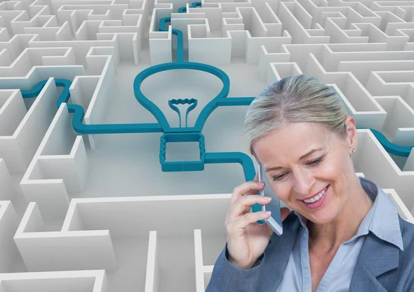 Affärskvinna med hjälp av smart telefon mot glödlampa ansluten i labyrint — Stockfoto