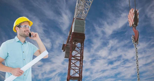 Arkitekt med mobiltelefon medan du håller blå utskrift av crane mot himlen — Stockfoto
