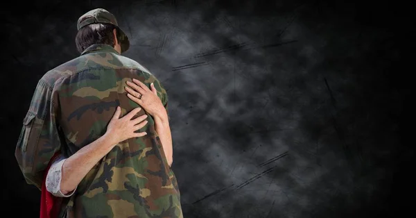 Costas de soldado sendo abraçado contra fundo grunge preto — Fotografia de Stock