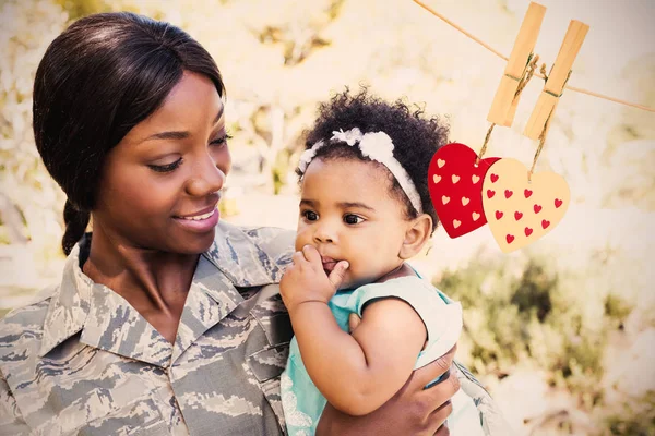 Female soldier carrying daughter at park — Stock Photo, Image