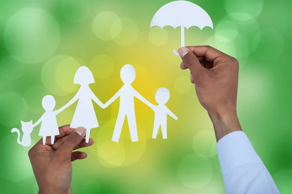Hand hält einen Regenschirm und eine Familie in Papier — Stockfoto