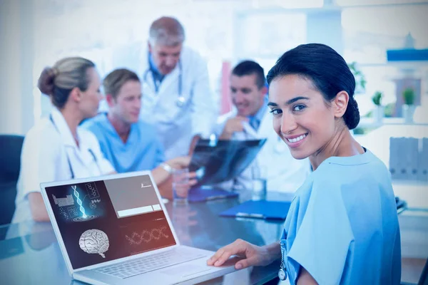 Hermosa sonriente médico escribiendo en el teclado con su equipo detrás — Foto de Stock