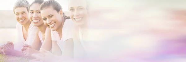 Smiling women lying in row and wearing pink for breast cancer — Stock Photo, Image