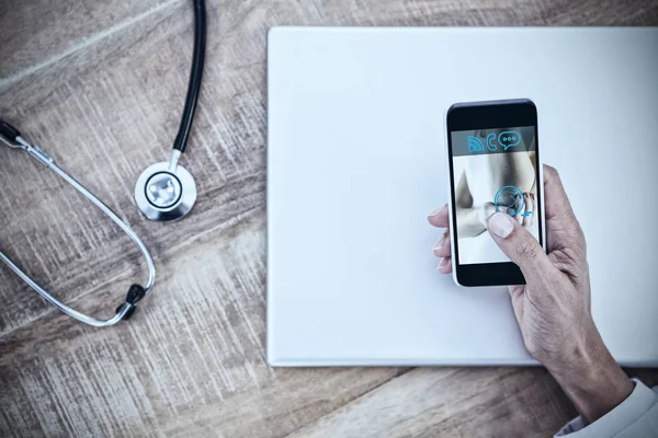 Γιατρός χρησιμοποιώντας smartphone στο ξύλινο γραφείο — Φωτογραφία Αρχείου