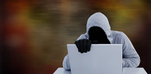 Hacker em capuz cinza e luvas usando laptop — Fotografia de Stock