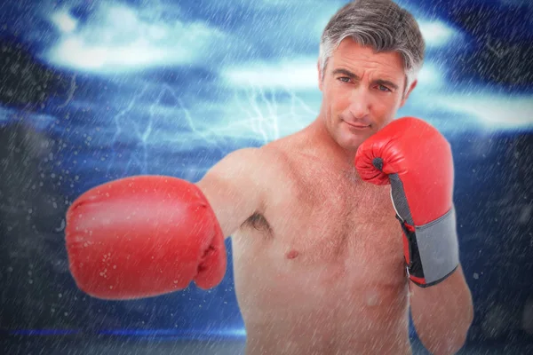 Imagen compuesta de hombre en forma perforando con guantes de boxeo — Foto de Stock