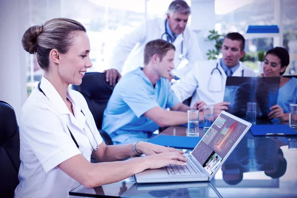 Beautiful smiling doctor typing on keyboard with her team behind — Stock Photo, Image