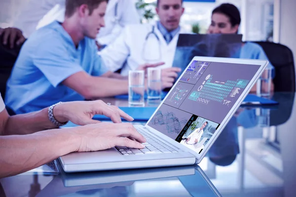 Medico digitando sulla tastiera con il suo team dietro — Foto Stock