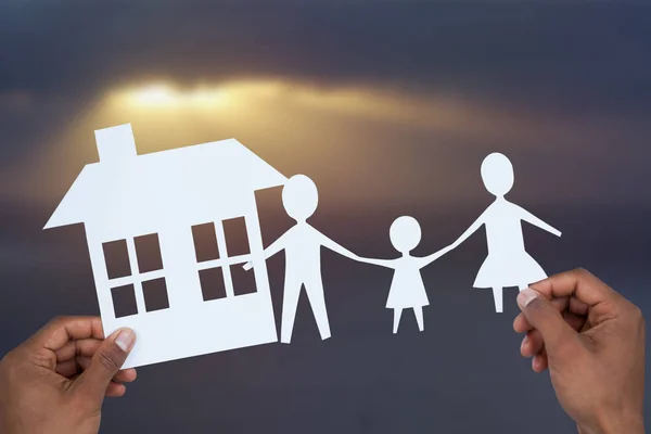 Handen met een gezin met haar huis in papier — Stockfoto