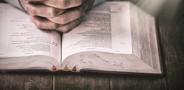 Sección media del hombre rezando con la Biblia —  Fotos de Stock