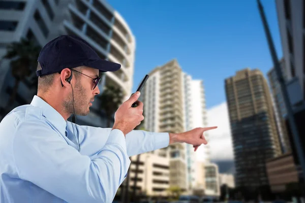 Oficial apontando para longe enquanto fala sobre walkie talkie — Fotografia de Stock