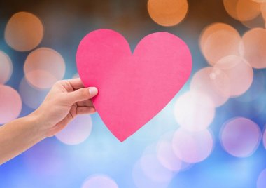 Parlak ışık bokeh arka plan ile kalp tutan el