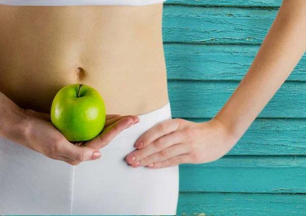 Žena, fitness. Apple a břicho světle modré dřevěné pozadí — Stock fotografie