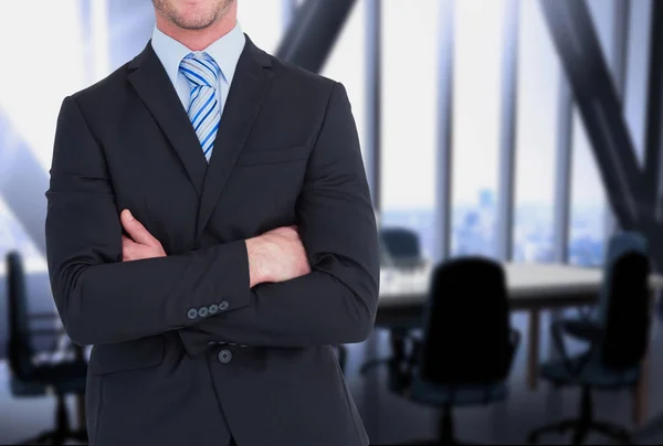 Hombre de negocios cruza sus brazos contra fondo de oficina — Foto de Stock