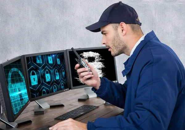 Bewaker met sloten op de schermen spreken met de walkie-talkie in zijn kantoor — Stockfoto