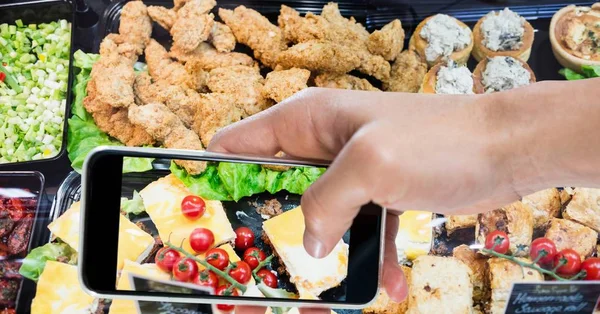 Beskurna hand tog bilden av olika mat genom smart telefon — Stockfoto