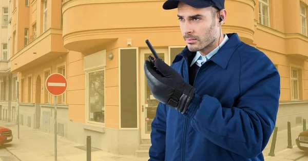 Segurança segurando walkie talkie enquanto em pé na estrada contra edifícios — Fotografia de Stock