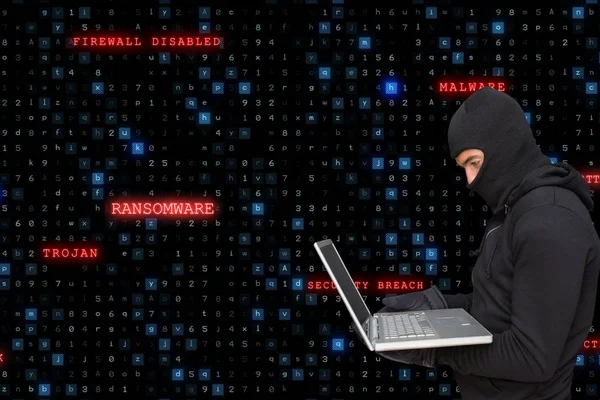 Sied syn på cyber kriminella bär en huva är hacka från en bärbar dator mot matris kod regn bakgr — Stockfoto