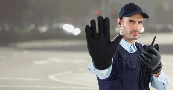 Guarda de segurança com walkie talkie e mão para cima contra a rua embaçada — Fotografia de Stock