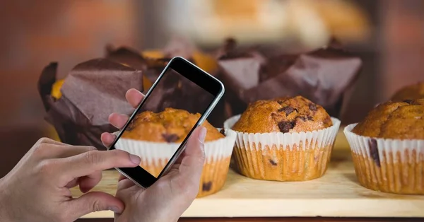 Mão fotografar muffins através de telefone inteligente na padaria — Fotografia de Stock