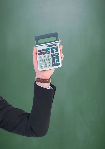 Hand with calculator against green chalkboard — Stock Photo, Image