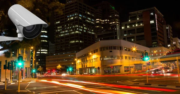 Câmera CCTV contra trilhas de luz na cidade à noite — Fotografia de Stock