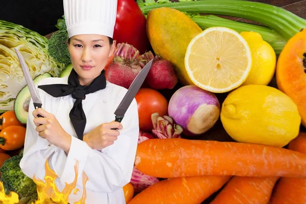 Jefe sosteniendo cuchillos con un fondo de verduras —  Fotos de Stock