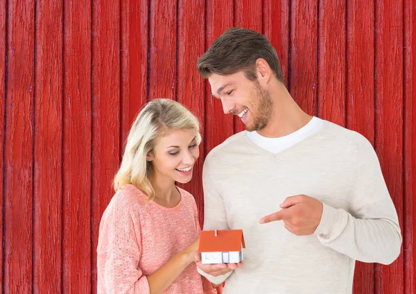 Par med lilla hus i händerna med röd trä bakgrund — Stockfoto