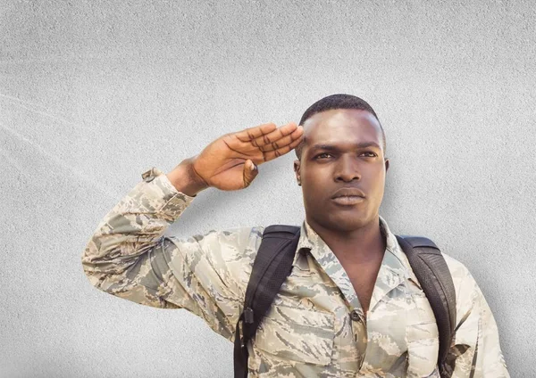 Serious soldier saluting. Concrete wall — Stock Photo, Image