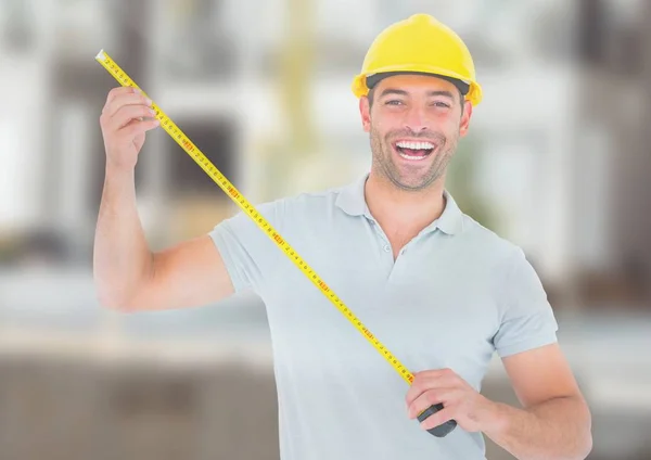 Construction Worker with measuring tape in front of construction site