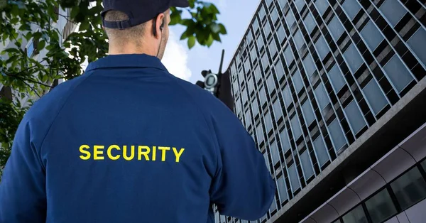 Vista trasera del guardia de seguridad hablando en walkie talkie mientras está de pie en la ciudad — Foto de Stock