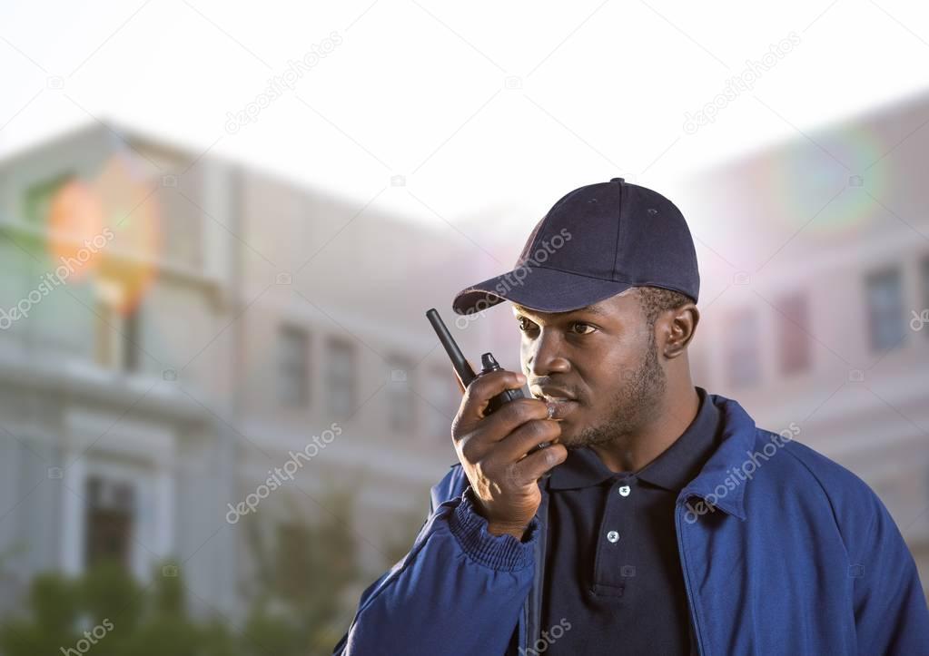 security guard speaking with the walkie-talkie in front of a building