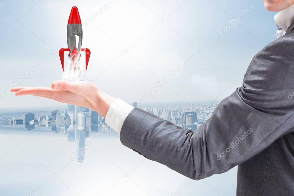 A businessman is holding a rocket taking off from his hand against blue background 