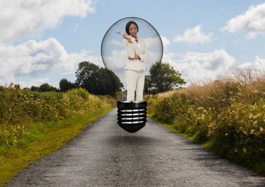 Businesswoman standing in bulb over road against sky clipart