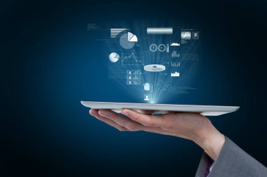 Elini bir tablet bilgisayar projelendirme grafik mavi arka plan karşı hologramlar tutuyor 