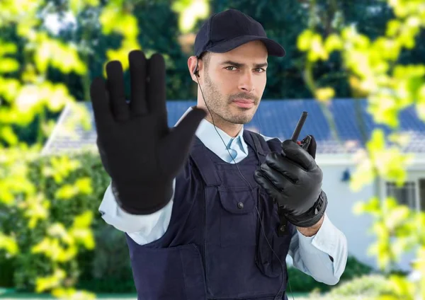 Guarda de segurança com chapéu, fone de ouvido e walkie-talkie, dizendo parar com a mão na frente do hous — Fotografia de Stock