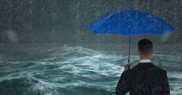 Zadní část obchodní muž s deštníkem proti bouřlivé moře s deštěm — Stock fotografie