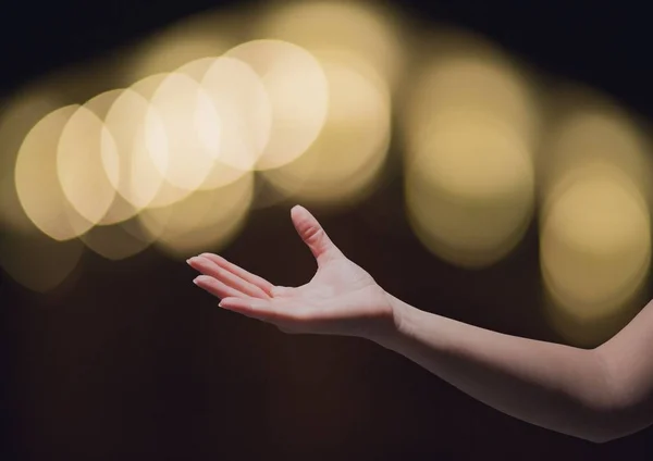 Mão chegando perguntando em maravilha com espumante luz bokeh fundo — Fotografia de Stock