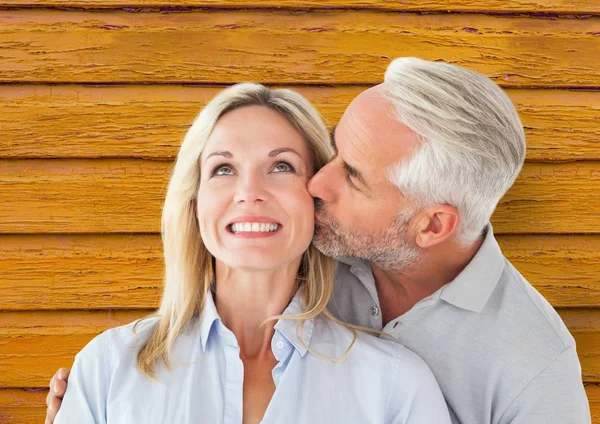 Coppia: uomo che dà un bacio alla donna con fondo in legno giallo — Foto Stock